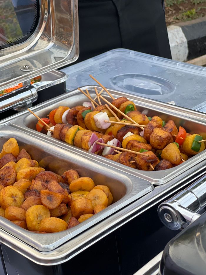 Tasty buffet with fried plantains and skewers, perfect for outdoor gatherings. Vibrant and colorful selection.