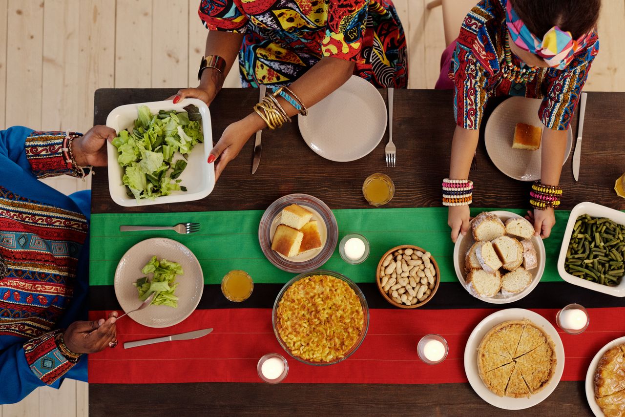 Accueil Top view of a family enjoying a Kwanzaa feast with traditional foods and vibrant attire.