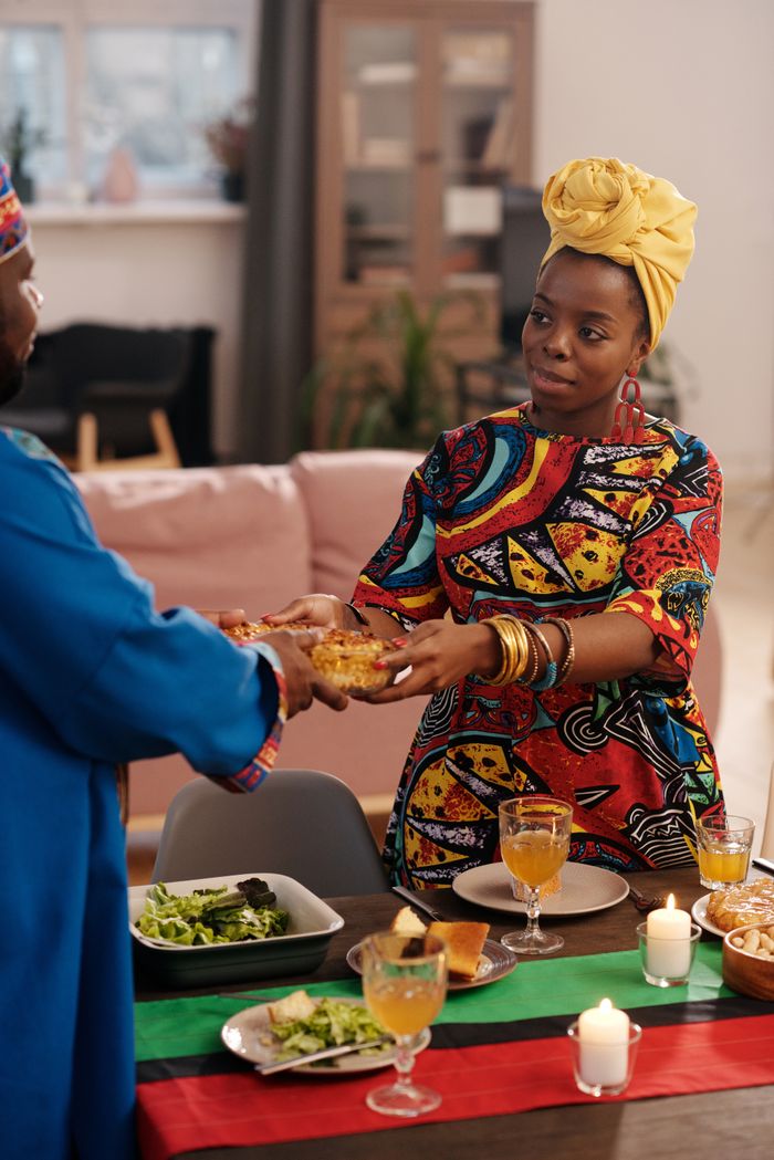A joyful Kwanzaa celebration featuring traditional African dishes and attire indoors.